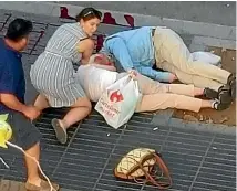  ?? PHOTO: REUTERS ?? Bystanders rushed to help people injured after a white van zig-zagged at high speed down Las Ramblas, sending some victims hurtling through the air.