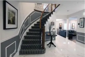  ?? TRACY HANES ?? NOW A new dark wood stair railing, updated pickets and patterned carpet, plus large-scale tile flooring and contrastin­g paint, combine to give the front foyer a sleek, modern look.