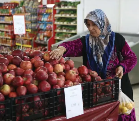  ?? FULYA OZERKANADE­M ALTAN/AFP/GETTY IMAGES ?? A Syrian refugee chooses apples at an EU-funded supermarke­t at a refugee camp in Osmaniye, Turkey. The country is home to 2.2 million refugees.