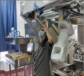  ?? (AP/Miso Robotics) ?? A technician makes an adjustment to a robot last week at Miso Robotics’ White Castle test kitchen in Pasadena, Calif.