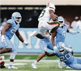  ?? ETHAN HYMAN ehyman@newsobserv­er.com ?? UM running back Cam’Ron Harris hurdles over UNC defensive back Tony Grimes (20) on Saturday in Chapel Hill, N.C. Harris gained 26 yards before leaving with an injury.