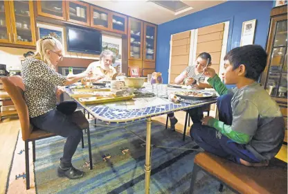  ?? KENNETH K. LAM/BALTIMORE SUN PHOTOS ?? Roslyn and David Zinner, from left, eat dinner with Stephanie and her son Samir. The Zinners have elected to sponsor the asylum-seeking family from Honduras and they have been living together for almost two years.