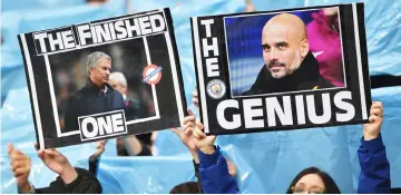  ?? — AFP photo ?? Manchester City fans hold up placards showing the faces of Pep Guardiola (right) and Jose Mourinho (left) during the English Premier League at the Etihad Stadium in Manchester, north west EnglandIn in this April 07 file photo.