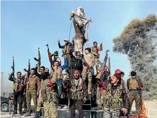  ?? PHOTO:AP ?? Turkey-backed Free Syrian Army soldiers celebrate around a statue of Kawa, a mythology figure in Kurdish culture, as they prepare to destroy it in the city centre of Afrin, north-western Syria.