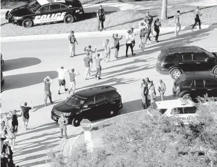  ?? MIKE STOCKER/SUN SENTINEL ?? Students hold their hands in the air as they are evacuated by police from Marjory Stoneman Douglas High School in Parkland on Feb. 14 after a shooter opened fire on the campus.