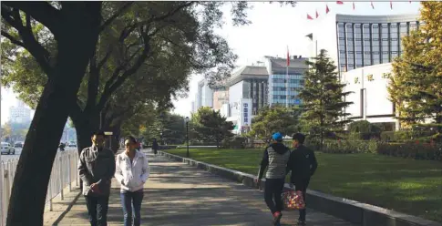  ??  ?? Pedestrian­s walk past the People’s Bank of China headquarte­rs (right) in Beijing. Chinese banks extended $182bn in net new yuan loans in November, slightly more than analysts had expected and up from the previous month, according to data published by the central bank yesterday.