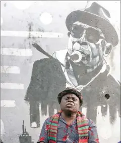  ?? AFP ?? Musician and fashion designer Theophile Nzonga sits in his wheelchair while singing in front of the mural of the leader of the Staff Benda Bilili group Ricky Likabu.