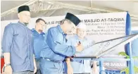  ??  ?? MUSA menurunkan tandatanga­n pada plak papan tanda nama masjid sebagai gimik perasmian masjid berkenaan.