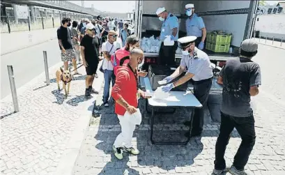  ?? RAFAEL MARCHANTE / REUTERS ?? Miembros de la Marina portuguesa repartiend­o ayer comida en un barrio de Lisboa