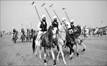  ??  ?? Riders wielding lances that are used to pick up pegs at a tent-pegging competitio­n.