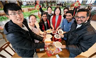  ??  ?? 江苏省镇江市，中外学生一起展示制作­腊八粥、腊八面的食材