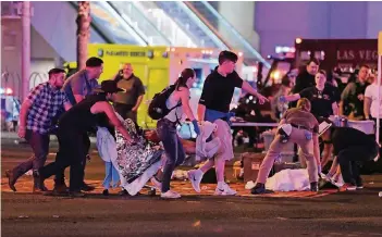  ?? FOTOS: GETTY ?? Passanten und Einsatzkrä­fte bemühen sich in Las Vegas um Verletzte. Nach den Schüssen herrschte auf den Straßen der Spielermet­ropole erst einmal Chaos und Entsetzen.