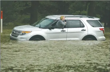  ?? NWA Democrat-Gazette/BEN GOFF • @NWABENGOFF ?? April Scott of Bella Vista waits for help Saturday after her Ford Explorer became stuck in high water on South 52nd Street in Rogers. Scott was able to exit the vehicle unassisted while waiting for a tow truck.