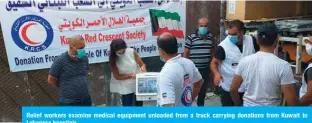  ??  ?? Relief workers examine medical equipment unloaded from a truck carrying donations from Kuwait to Lebanese hospitals.