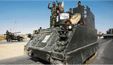  ?? — AFP ?? Men on a mission: Members of the Popular Mobilisati­on Units supporting Iraq’s government forces driving an armoured personnel carrier on the outskirts of the Iraqi city of Najaf.