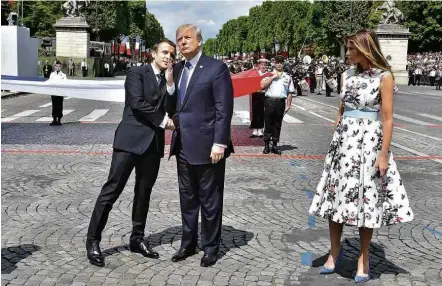  ?? Christophe Archambaul­t/AFP ?? O presidente da França, Emmanuel Macron, cochicha ao lado de Trump, com a primeira-dama Melania Trump à direita