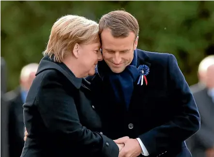  ?? AP ?? French President Emmanuel Macron holds the hands of German Chancellor Angela Merkel during a ceremony in Compiegne, north of Paris. US President Donald Trump missed the meeting because of rain.