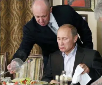  ?? MISHA JAPARIDZE, POOL - THE ASSOCIATED PRESS ?? In this 2011 photo, Yevgeny Prigozhin, left, serves food to Russian Prime Minister Vladimir Putin during dinner at Prigozhin’s restaurant outside Moscow, Russia. Progozhin is known as “Putin’s chef” — a wealthy Russian businessma­n and restaurate­ur who...