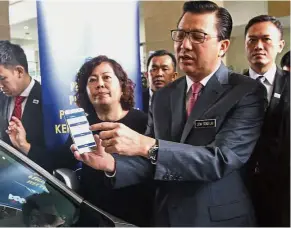  ??  ?? Screen test: Liow showing the specificat­ions of the tint he scanned with his smart phone during the launch of the tint standardis­ation mechanism in Putrajaya.