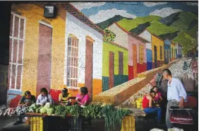  ??  ?? CARACAS: Vegetable vendors wait for customers behind their tables set up on the sidewalk, in front of a mosaic in Caracas, Venezuela. Shoppers have been scared off by prices that double every few weeks as wages in the crisis-wracked nation remain...