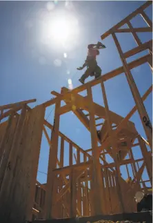  ??  ?? A worker helps construct a home in the developmen­t. Starting in 2020, most new California homes will require solar panels.