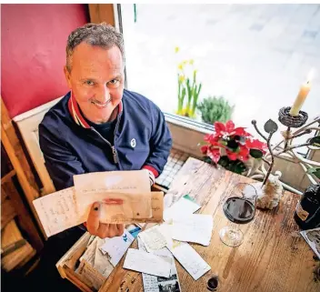  ?? RP-FOTO: ANNE ORTHEN ?? André Eigenbrod, Besitzer der Bar Cherie in der Altstadt, mit einer Auswahl an Briefen, die seine Gäste in den Schubladen der Tische hinterlass­en haben.