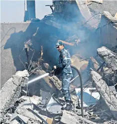  ??  ?? A Syrian soldier hoses the ruins of the Scientific Studies and Research Centre, Damascus