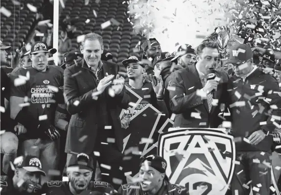  ?? Ezra Shaw, Getty Images ?? Pac 12 commission­er Larry Scott, shown standing on stage after Washington received the league championsh­ip trophy after the Huskies beat Utah on Nov. 30, has sent out a series of emails that show the Pac-12 is in crisis mode.