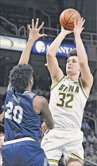  ?? Lori Van Buren / Times Union ?? Siena’s Evan Fisher goes up for a shot against Saint Peter’s Derrick Woods during a basketball game at Times Union Center in Albany on Tuesday. Fisher scored a game-high 21 points in the victory.