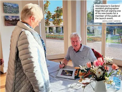  ?? ABERGLASNE­Y GARDENS ?? Aberglasne­y’s Gardens’ resident photograph­er Nigel Mccall signing one of his new books for a member of the public at the launch event.