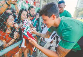  ??  ?? Pedro autografa a camisa da torcedora durante treino nas Laranjeira­s