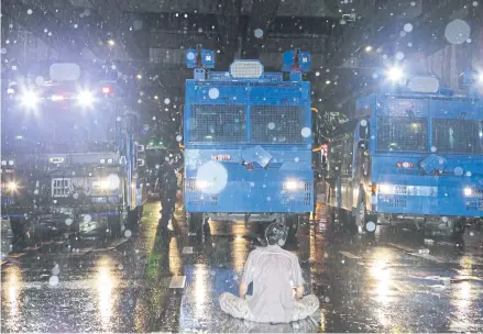  ?? APICHIT JINAKUL ?? A lone protester sits in front of police water cannon trucks to prevent them from advancing on demonstrat­ors who gathered peacefully at Pathumwan intersecti­on on Friday.