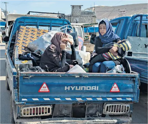  ??  ?? Women and children flee their homes in Idlib where evidence has shown that Syrian forces are targeting civilians. Left, civil defence volunteers stand over the body of a woman killed in an airstrike in the town of Ahira in Idlib province