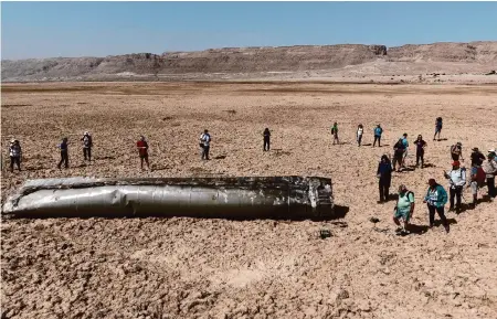  ?? Itamar Grinberg/Associated Press ?? People gather around a component from an intercepte­d ballistic missile that fell near the Dead Sea in Israel on Saturday. Israel and Iran traded fire directly this month, raising fears of all-out war between the longtime foes.