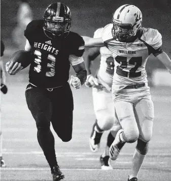  ?? Eric Christian Smith / Contributo­r ?? Heights running back Torrin Polk, left, slips by Bellaire defensive back Walter Truitt en route to a first-half touchdown Saturday at Delmar Stadium.