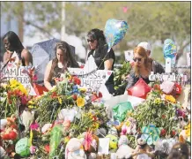  ?? David Santiago / TNS ?? Mourners bring flowers as they pay tribute at a memorial for the victims of the shooting at Marjory Stoneman Douglas High School on Feb. 25, during an open house as parents and students returned to the school for the first time since 17 people were...