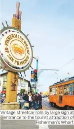  ??  ?? Vintage streetcar rolls by large sign at entrance to the tourist attraction of Fisherman’s Wharf.