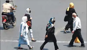  ??  ?? Iranians, mask-clad due to the coronaviru­s pandemic, cross a street in the capital Tehran, yesterday.