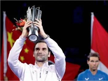  ??  ?? Switzerlan­d’s Roger Federer lifts Shanghai Masters trophy after defeating Rafael Nadal (right) of Spain in their men’s singles final on Sunday. —