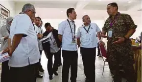  ?? PIC BY HAZREEN MOHAMAD ?? Election Commission chairman Azhar Azizan Harun (centre) checking the early voting process in Port Dickson yesterday.