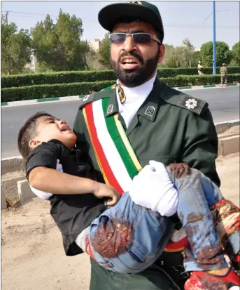  ?? Picture: Behrad Ghasemi ?? „ A Revolution­ary Guard carries a boy shot at a military parade.
