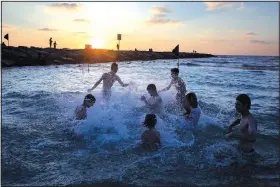  ?? (AP/Oded Balilty) ?? Israeli youth play in the water June 18 as the sun sets over Tel Aviv’s beach.