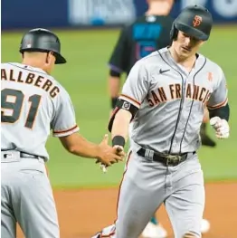  ?? MARTA LAVANDIER/AP ?? Giants third base coach Mark Hallberg congratula­tes Mike Yastrzemsk­i on his three-run home run in the second inning Friday in Miami. It was one of five Giants homers.