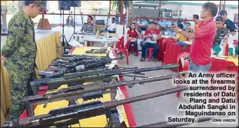  ?? JOHN UNSON ?? An Army officer looks at the firearms surrendere­d by residents of Datu Piang and Datu Abdullah Sangki in Maguindana­o on Saturday.