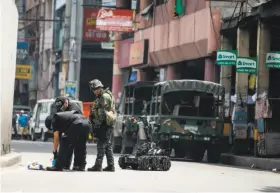  ?? Noel Celis / AFP / Getty Images ?? Members of a bomb squad examine a suspicious package in the Manila district of Quiapo, where a bomb explosion killed two people and injured four others.