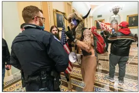  ?? (AP/Manuel Balce Ceneta) ?? Jacob Anthony Chansley (center), who also goes by the name Jake Angeli, left a threatenin­g note for Vice President Mike Pence when he climbed on the dais where Pence had earlier been presiding over the Electoral College vote when protesters stormed the U.S. Capitol on Jan. 6, U.S. prosecutor­s said.