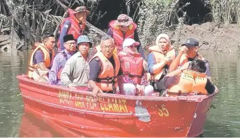  ?? ?? Bomba photo shows Nancy (seated front, second le operation for a crocodile a ack victim is on-going. ) and others on board a boat along the river, where the SAR