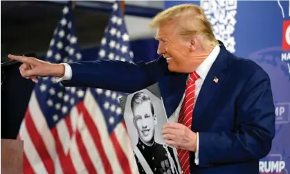  ?? Photograph: Andrew Harnik/AP ?? Donald Trump holds a photo of himself he got from a person in the crowd in Newton, Iowa, on 6 January 2024.