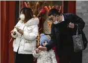  ?? ASSOCIATED PRESS ?? A man hands a sugar-coated Chinese haw to a child at the Qianmen pedestrian shopping street, a popular tourist spot in Beijing, on Tuesday.