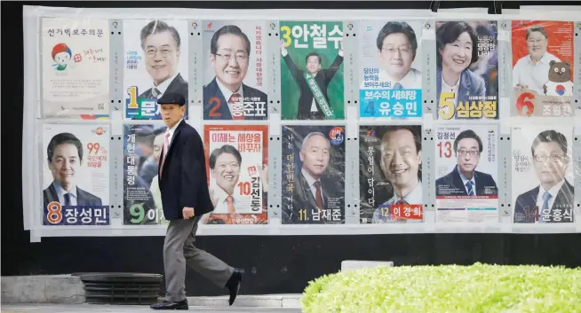  ??  ?? A man walks past posters of candidates for the upcoming presidenti­al election in Seoul on Sunday. (Reuters)